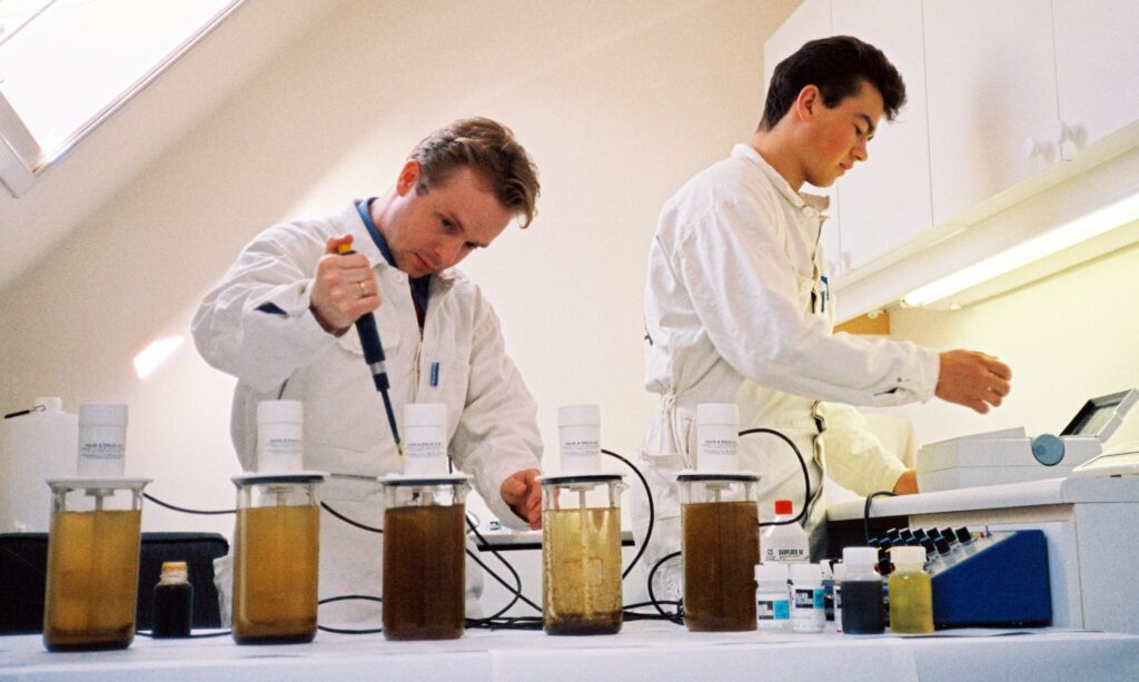 Laboratorieforsøk med fellingskjemikalier for rensing av avløpsvann. Kjell Schevig og Stian Olsson (bak).
